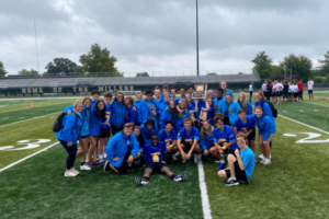 Picture of a Special Olympics Team wearing blue and embracing each other in a group phot.