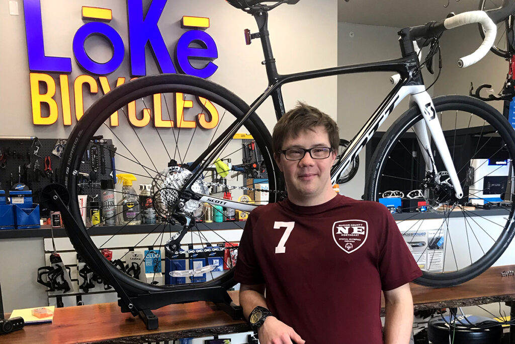 Tommy Sliva standing in front of a black and white mountain bike on a display rack.