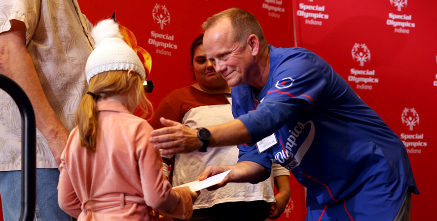 SOIN volunteer congratulating an athlete onstage for her achievement.