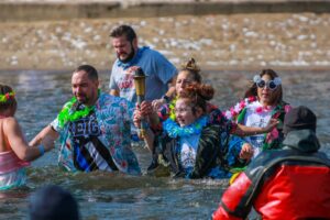 People wearing lays crossing a river carrying a torch