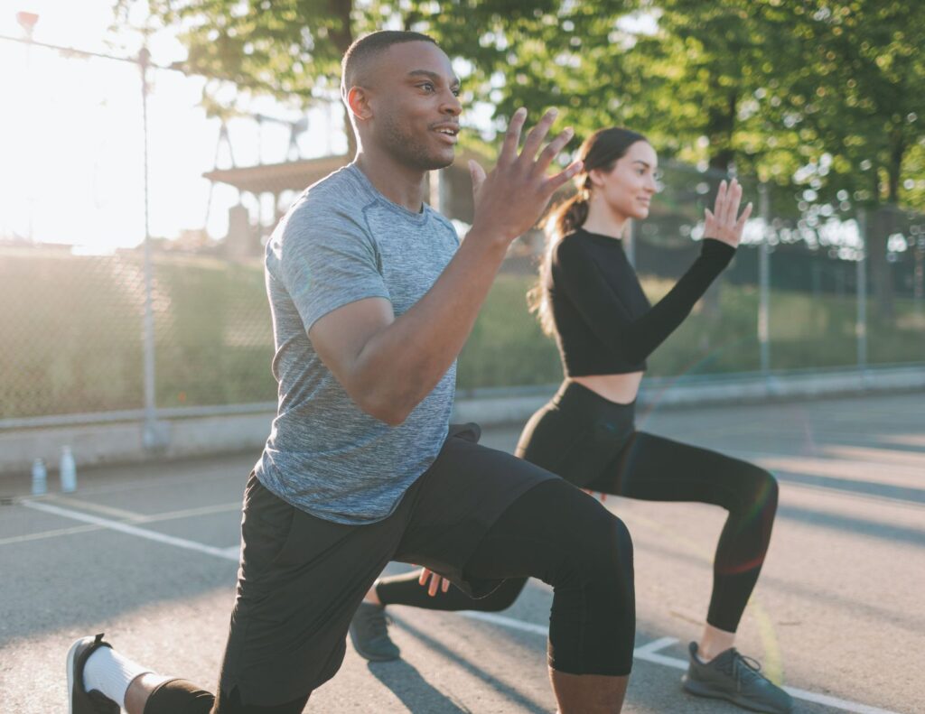 Man and women performing lunge exercise outside.