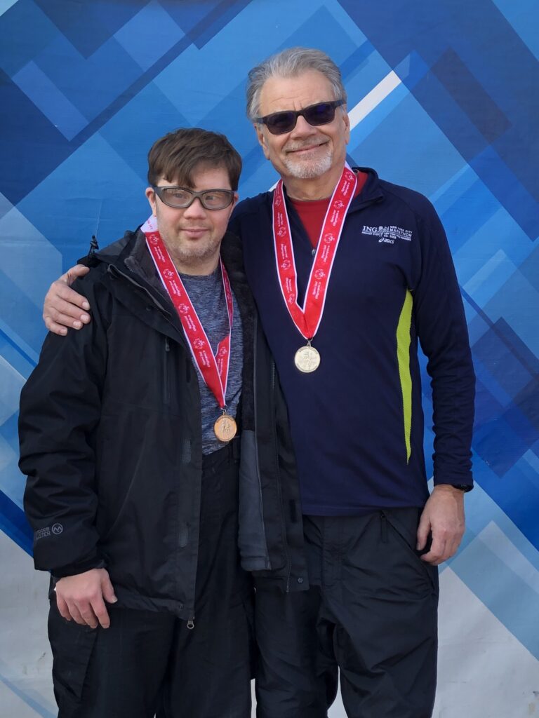 Thomas Sliva with coach Duncan Myers on the podium at Special Olympics Indiana World Winter Games