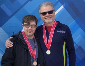 Thomas Sliva with coach Duncan Myers on the podium at Special Olympics Indiana World Winter Games