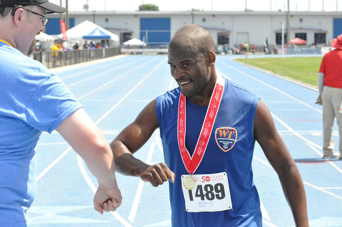 Two men arm bumping on a running track