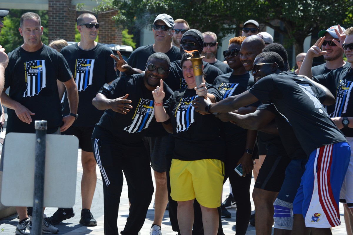 Group of athletes smiling for picture holding torch at event