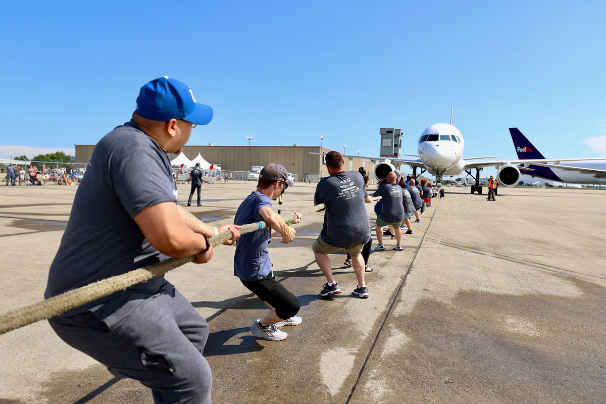 Group pulling plane by rope. Plane in distance, Image focused on the people.