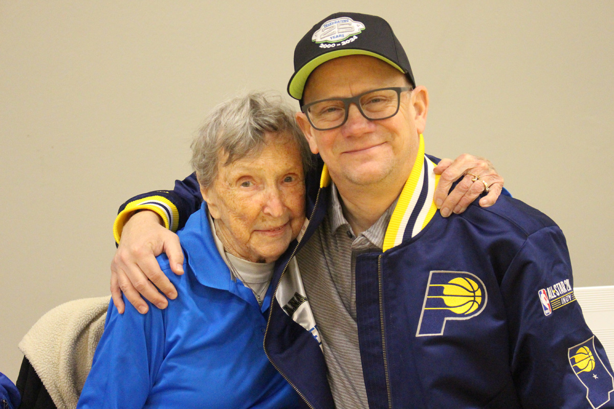 Man in pacers jacket hugging woman in blue polo