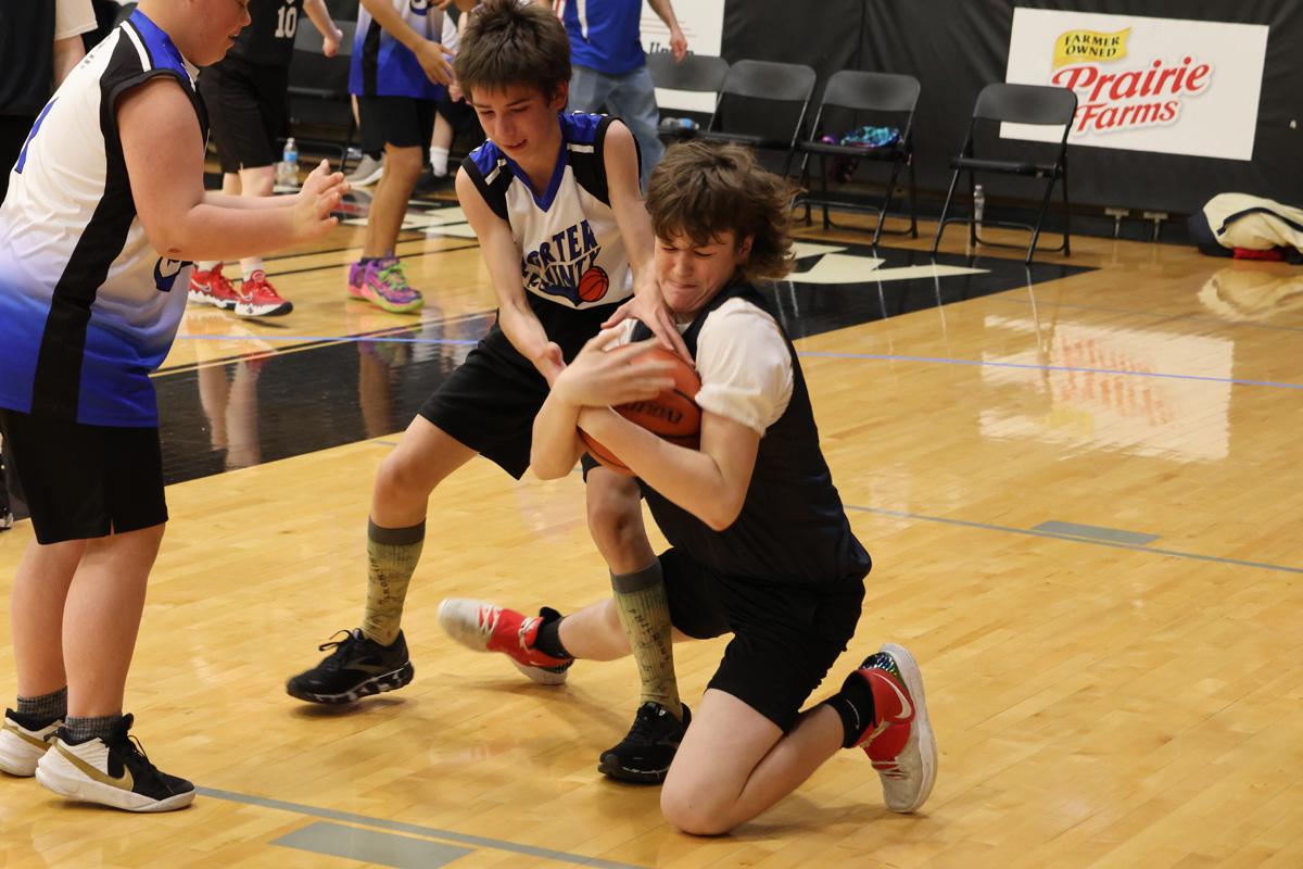 Basketball player tries to steal ball from other player.