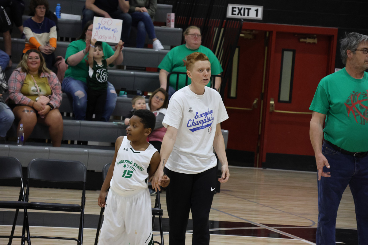 Athlete holding coaches hand while watching game on sidelines.