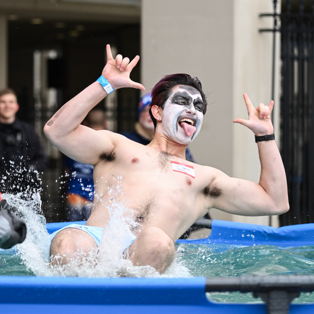 Man with painted face jumping into water.