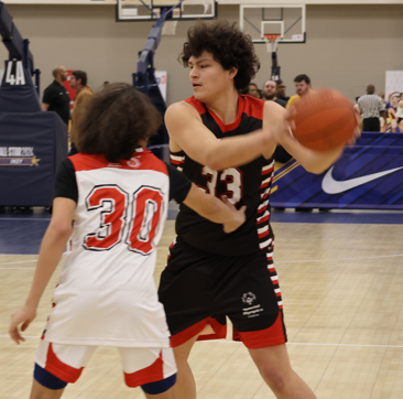 Two members of the Special Olympics playing on the court during a game. One of the players is about to pass the ball. 