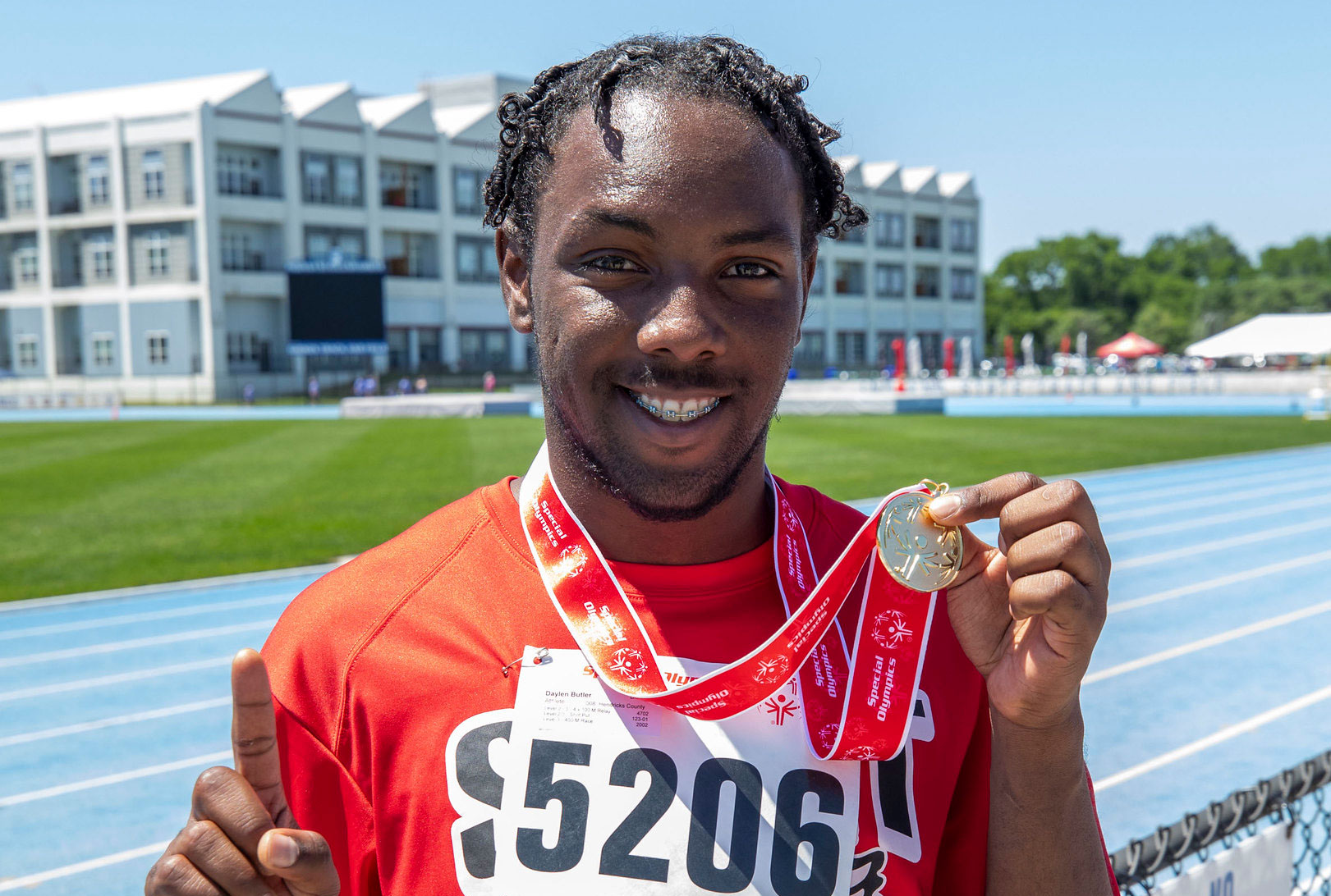 Man smiling holding a medal.