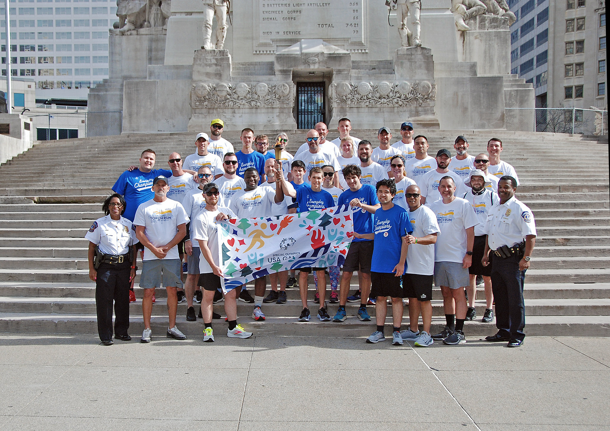 Group standing on stairs holding torch and team flag